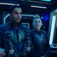 An intense-looking man and woman in military spacesuits stand on the bridge of a ship in a scene from The Expanse.